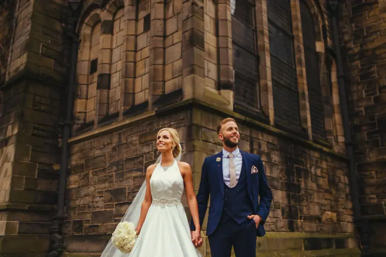 Leonnie and Andy walking hand in hand beneath the Gothic walls of Mansfield Traquair