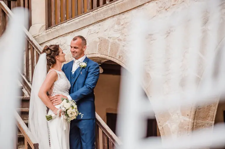 Bride and groom smiling by the wooden staircase of the monastery courtyard