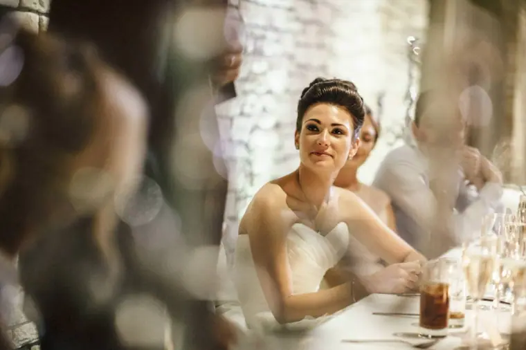 Bride smiling as she listens to the speeches, framed by soft bokeh