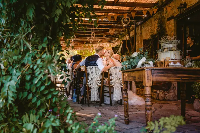 Guests dining at long tables beneath a vine-covered pergola