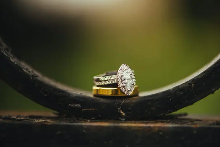 Diamond engagement ring and wedding bands balanced on curved iron railings