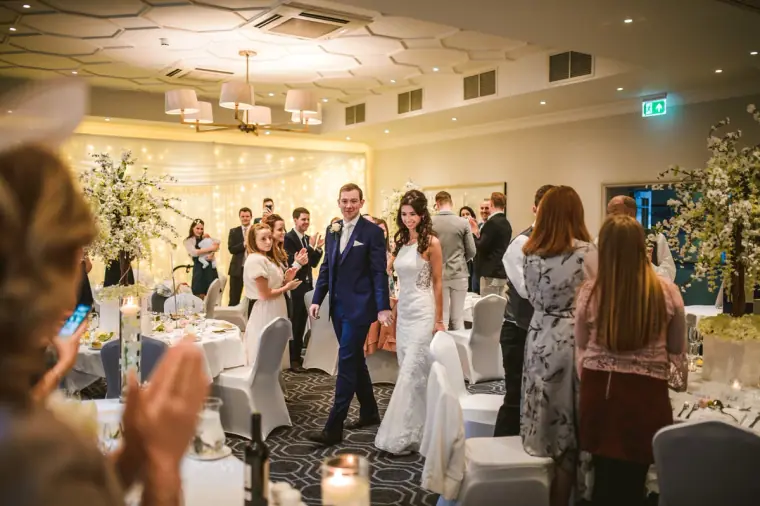 Guests applauding as the bride and groom enter the reception room