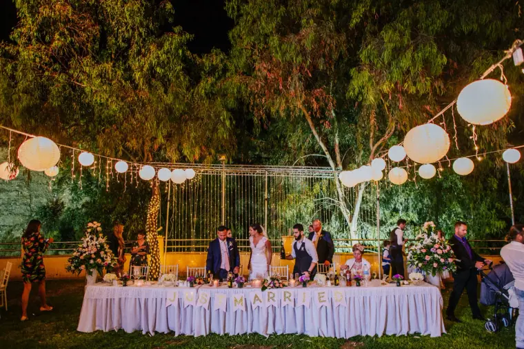 Evening reception tables under paper lanterns and trees at Hadjiantonas Winery, Limassol