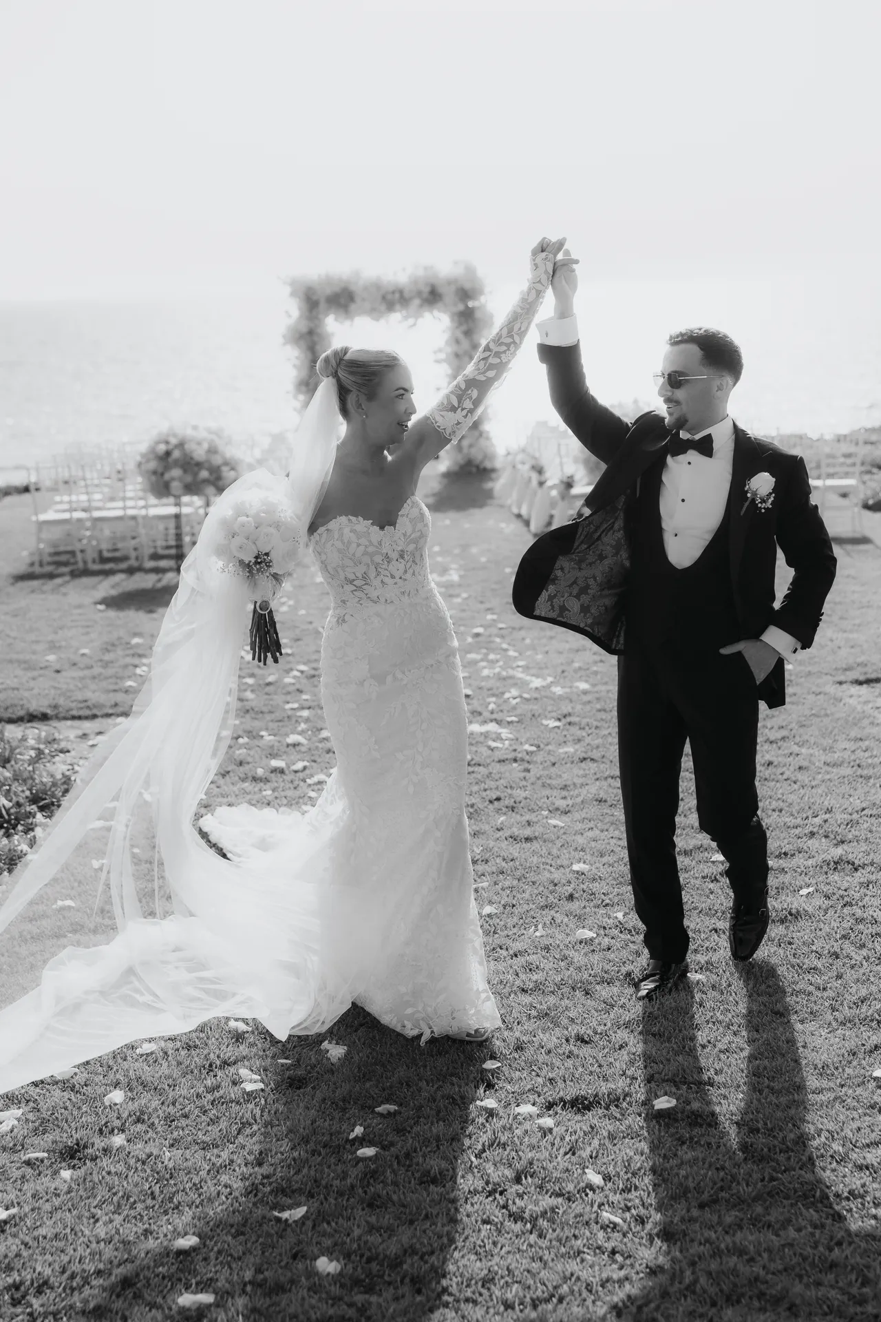 Black-and-white photo of the newlyweds raising joined hands in celebration
