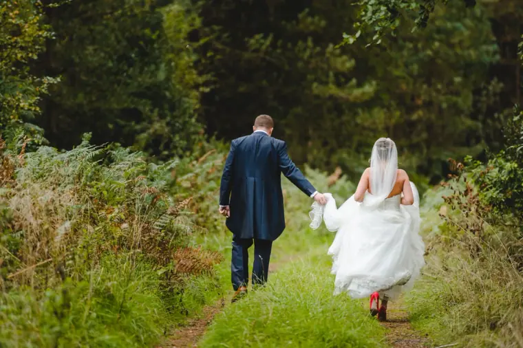 Sonny and Jo walking away hand in hand along a grassy woodland path