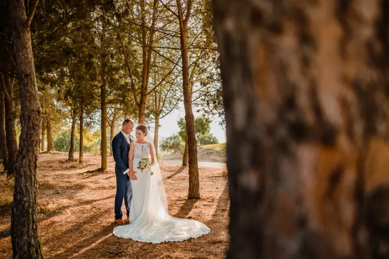 Couple among tall pine trees with long shadows across the needle-covered ground