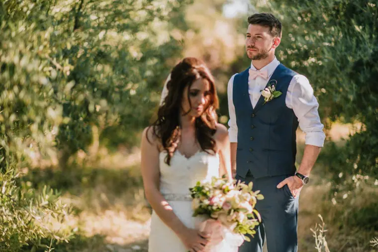 Claire holding her bouquet beside Sean among olive trees