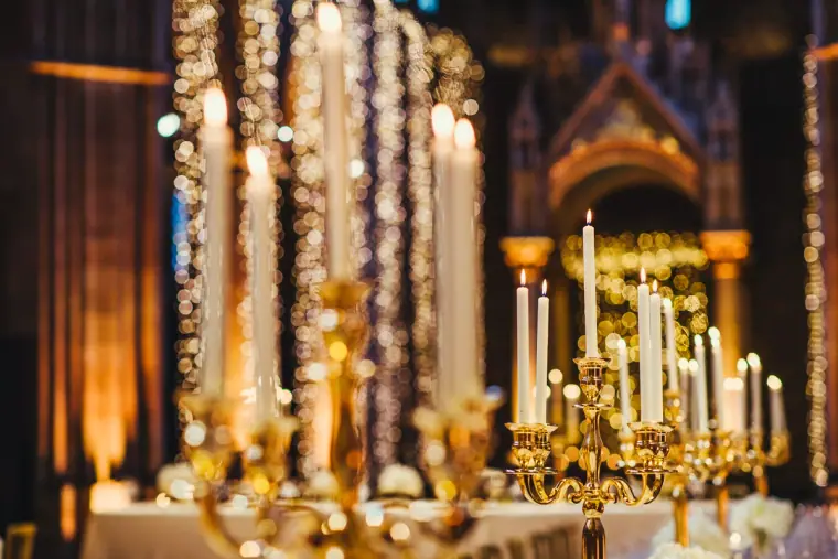 Gold candelabras and tall candles glowing on the reception tables