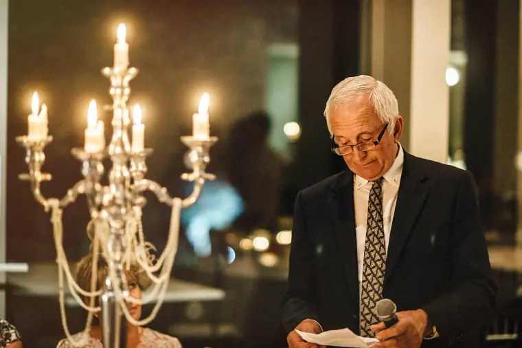 Father of the bride reading his speech beside a lit candelabra