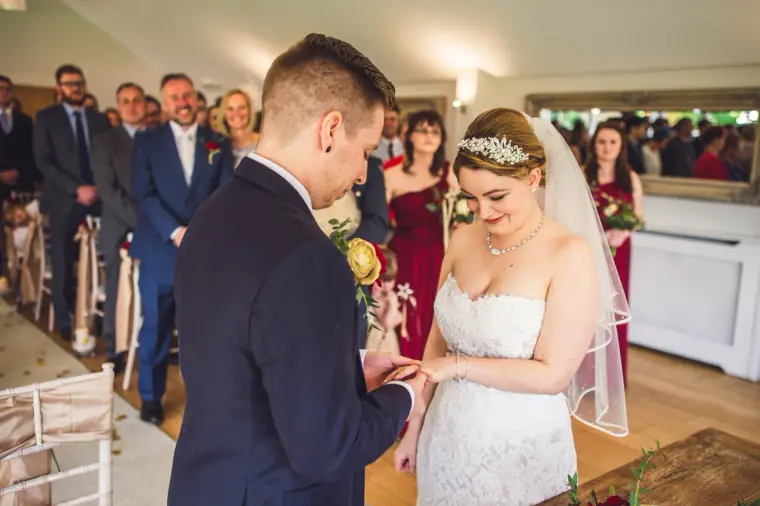 Charlie placing the ring on Sarah's finger during the ceremony at Wasing Park