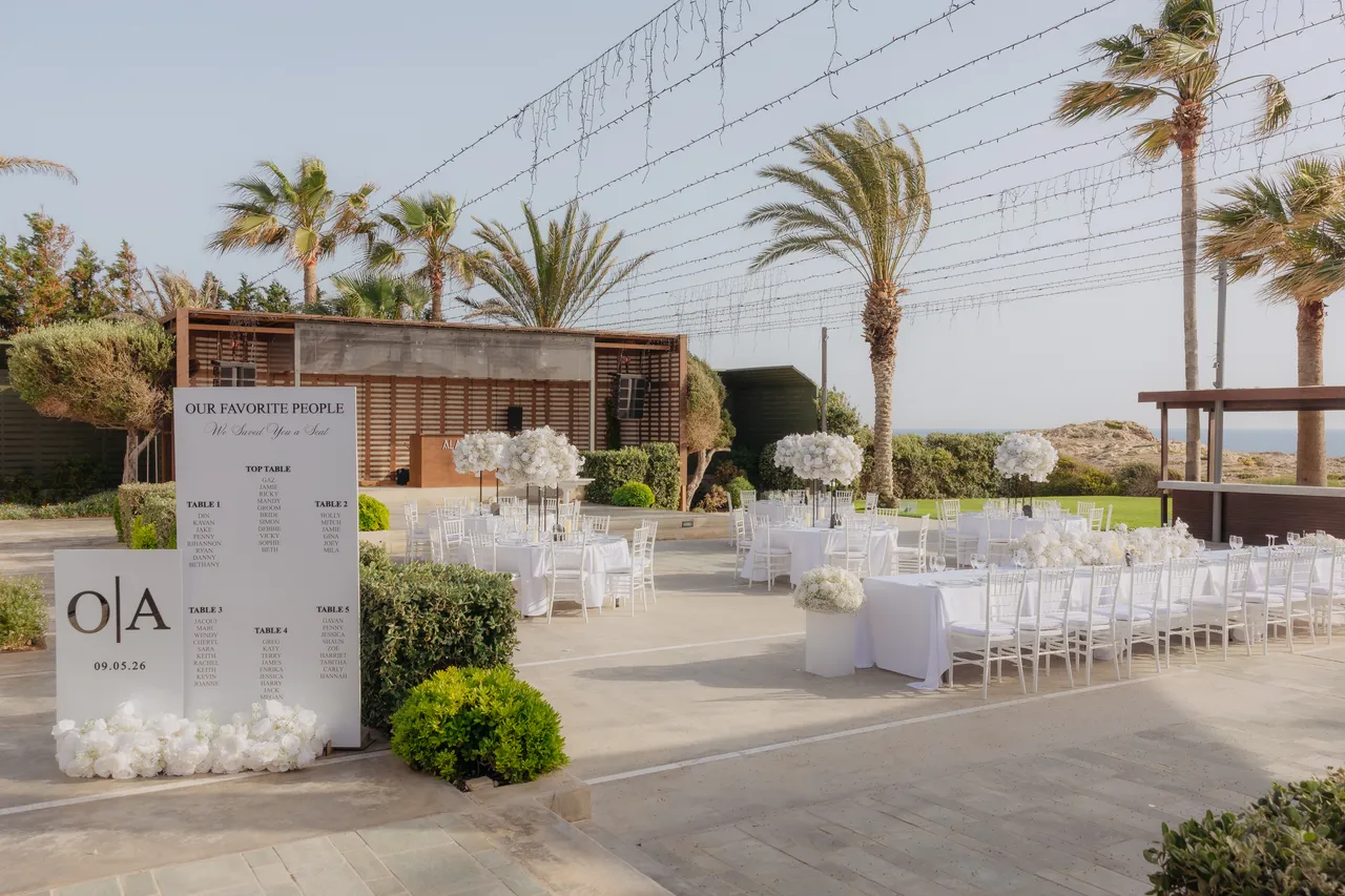 Reception terrace with an O|A table plan and white-dressed tables among palm trees at Alassos