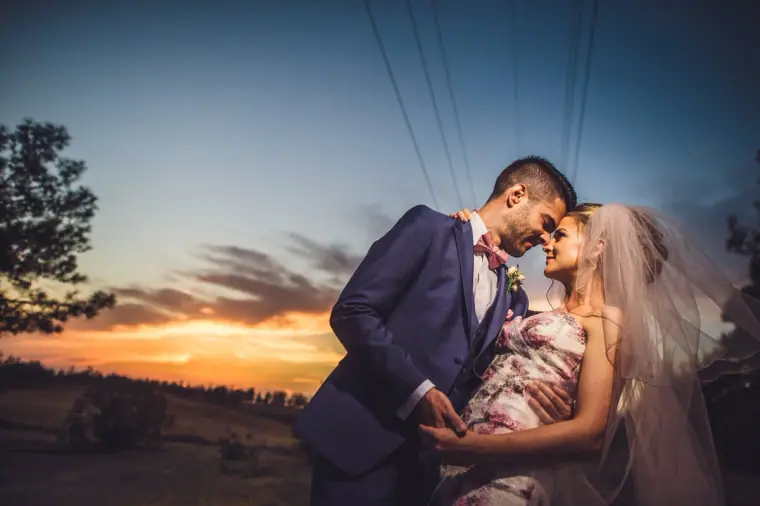 Groom dipping the bride against a vivid twilight sky