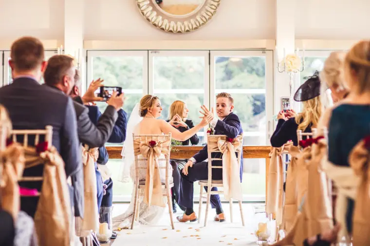 Guests photographing the couple as they sign the register at the front