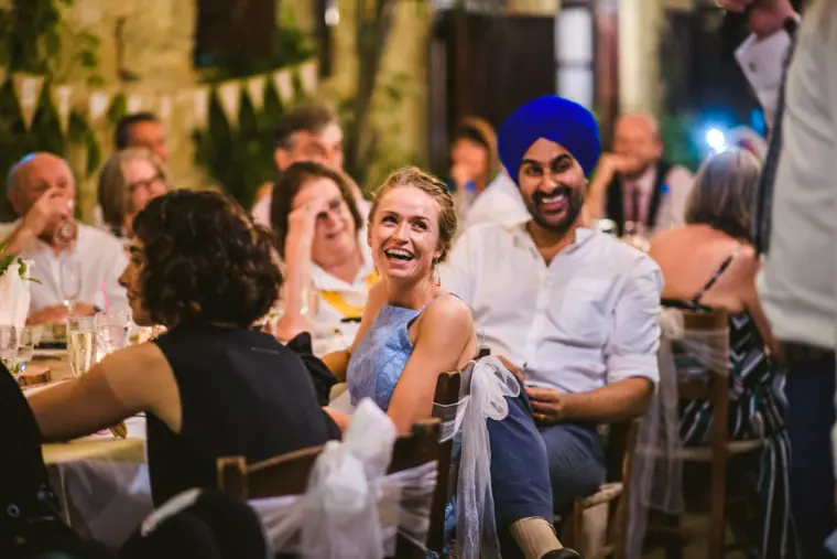 Guests laughing during the speeches at the reception beneath bunting