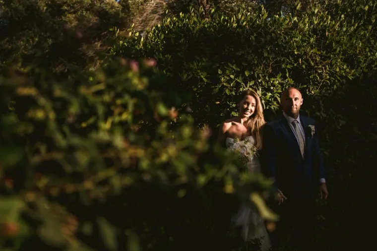 Couple standing together in deep green woodland, framed by leaves