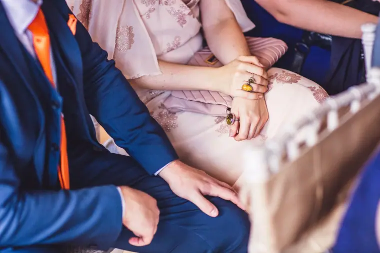 Guests' hands resting on their laps during the ceremony