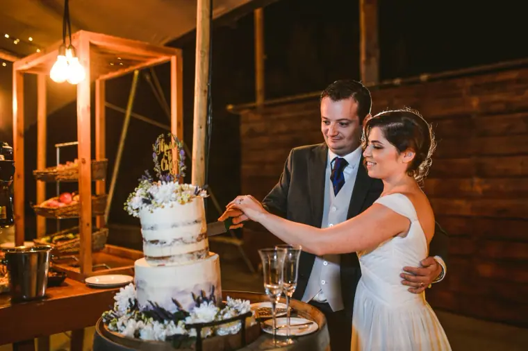 Bride and groom cutting the naked wedding cake under warm lights