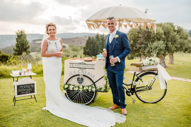 Bride and groom beside the traditional ice cream bicycle cart on the lawn