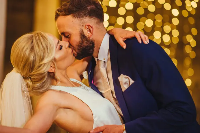 Andy kissing Leonnie in front of a wall of glowing bokeh lights