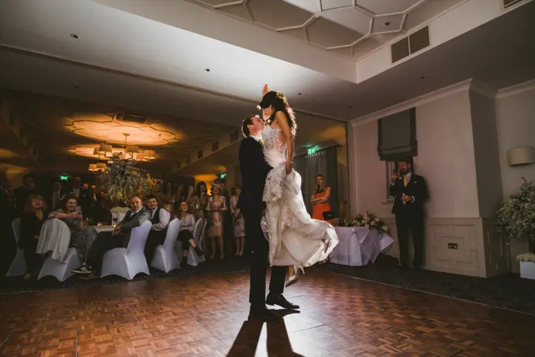 Iain lifting Elina off her feet during their first dance as guests watch