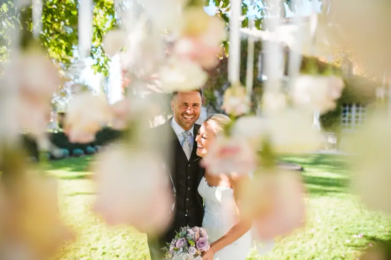 Sarah and Joe glimpsed through soft pink blossom in the garden at Chateau Rigaud