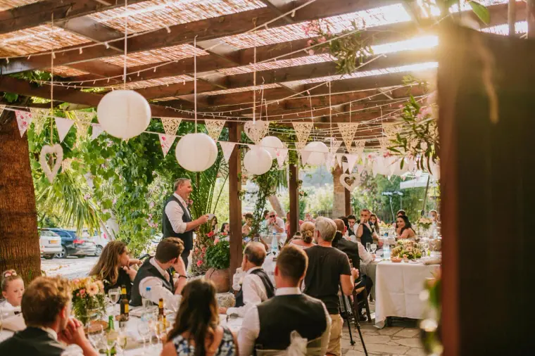 Guests seated under the pergola with paper lanterns during the speeches