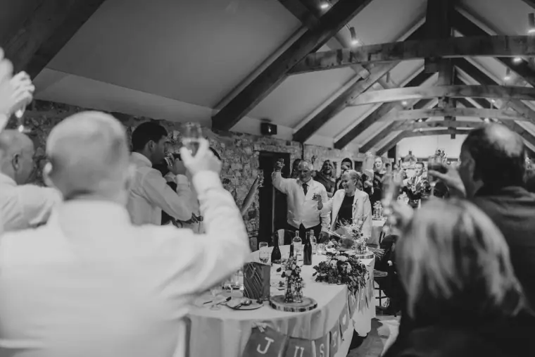 Black-and-white photo of guests raising glasses in a toast