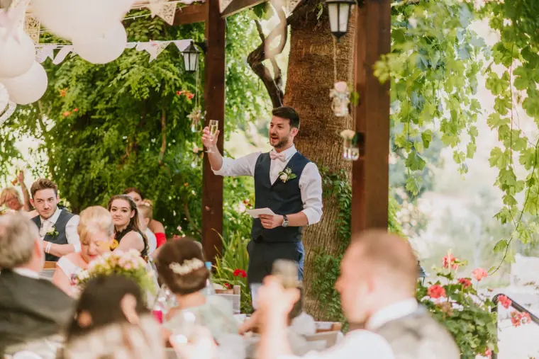 Sean standing to give his speech beneath lanterns and greenery