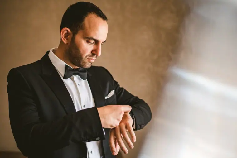 Groom in a tuxedo adjusting his cufflinks