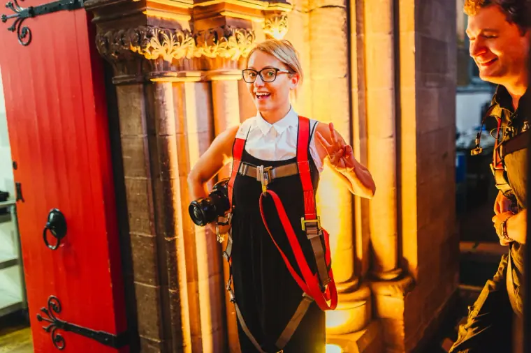 Photographer with two cameras laughing beside a red door