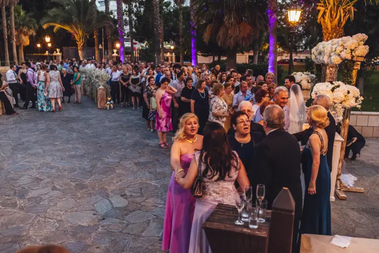 Guests mingling with drinks on a lantern-lit stone terrace at dusk