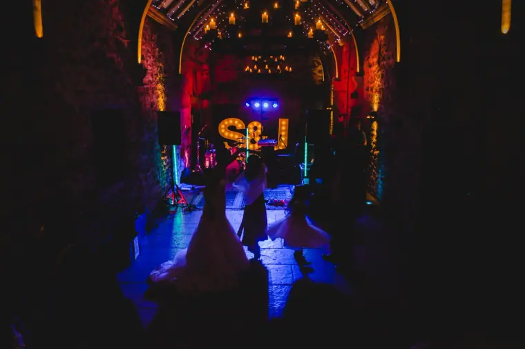 Couple dancing under coloured stage lights at the end of the barn
