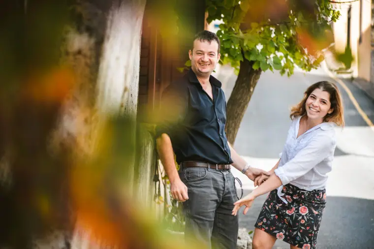 Couple laughing as they walk hand in hand down a village lane, framed by autumn leaves