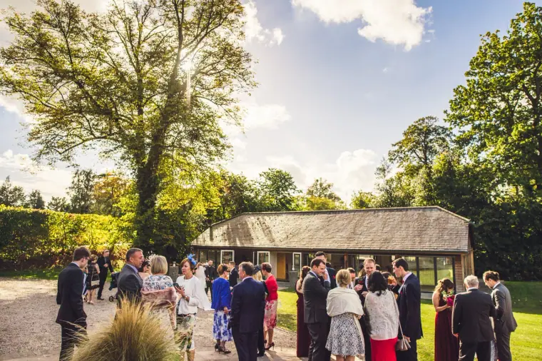 Guests gathered on the lawn beside a thatched pavilion at Wasing Park