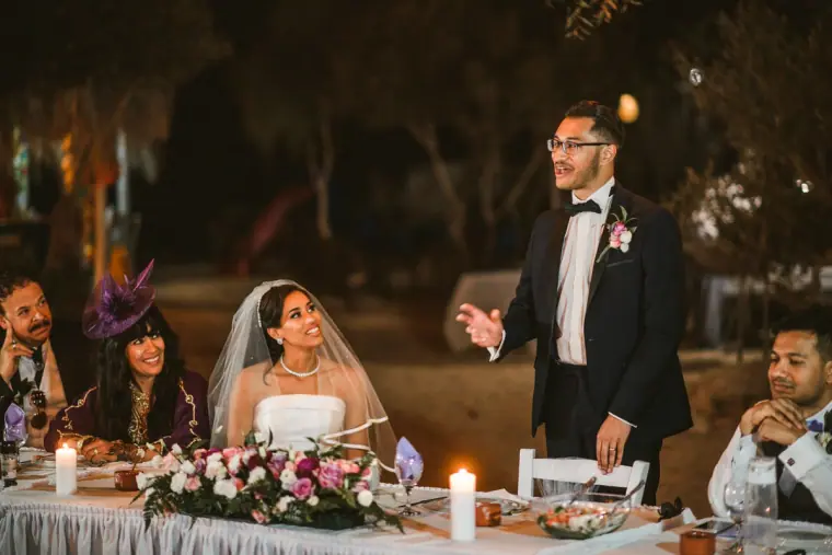 Groom giving his speech as the bride listens at the candlelit top table