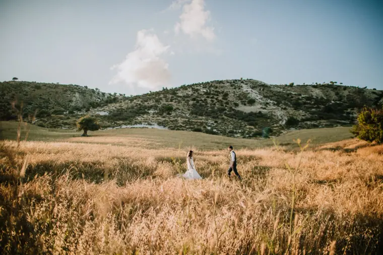 Couple walking through golden fields beneath rolling green hills near Vasilias Nikoklis Inn