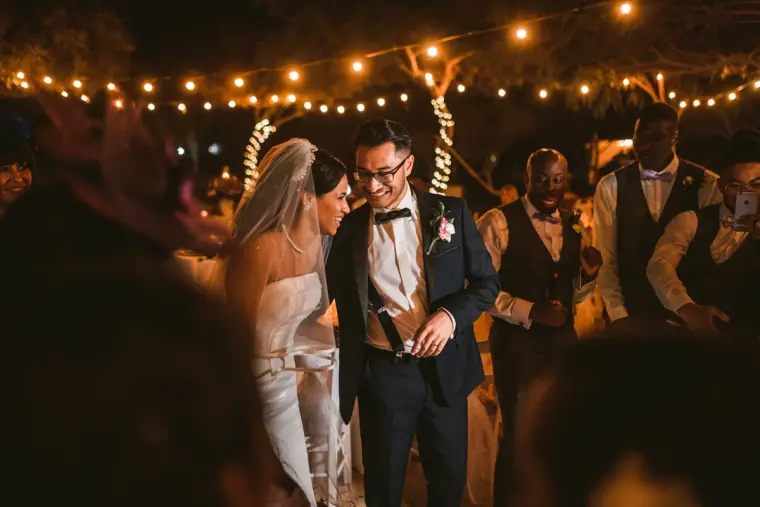 Bride and groom walking into the reception under strings of festoon lights
