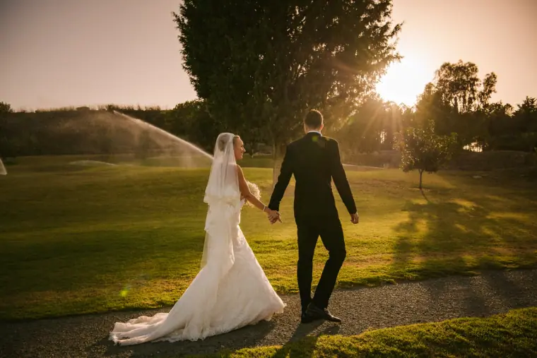 Couple walking hand in hand on a golf course lawn at sunset