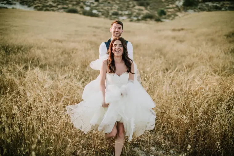 Claire running through long grass holding her skirt, Sean following behind