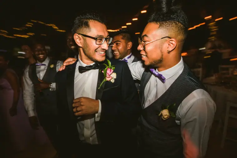 Groom and a groomsman laughing together on the dance floor