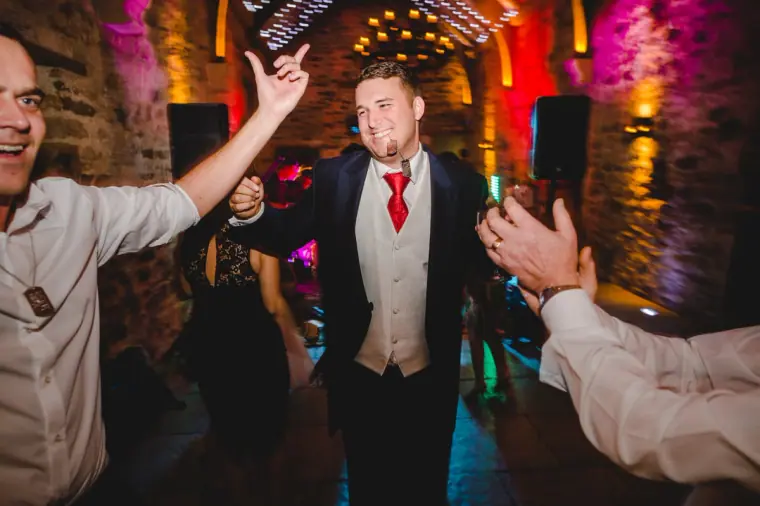 Groom dancing as guests cheer around him