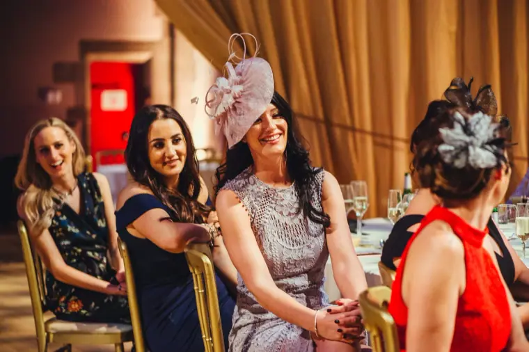 Female guests in fascinators laughing at the speeches