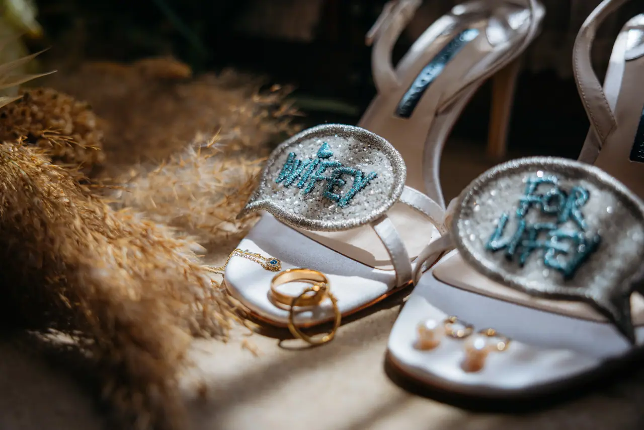 Bridal sandals with sequinned 'Wifey' and 'For Lifey' patches beside rings and pampas grass
