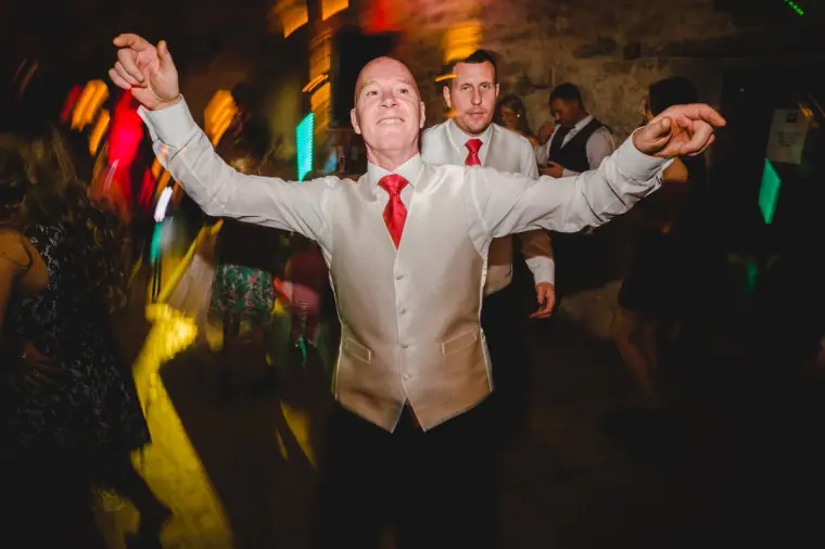 Guest in a waistcoat and red tie dancing with his arms outstretched