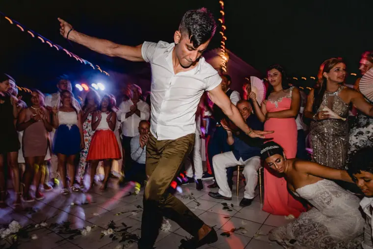 Guest dancing energetically as others cheer on a lively dance floor, Anassa