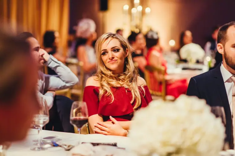 Guest in a red off-shoulder dress smiling during the speeches