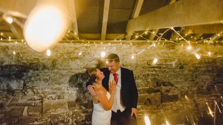Sonny and Jo slow dancing under strings of warm fairy lights