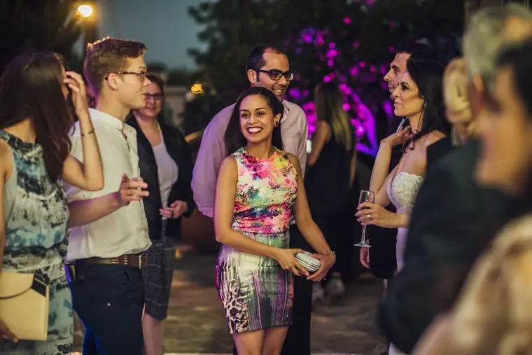 Smiling guests chatting in the garden under purple uplighting