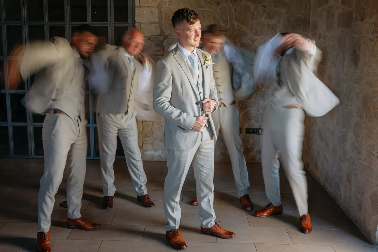 Groomsmen in light grey suits putting on their jackets at Liopetro