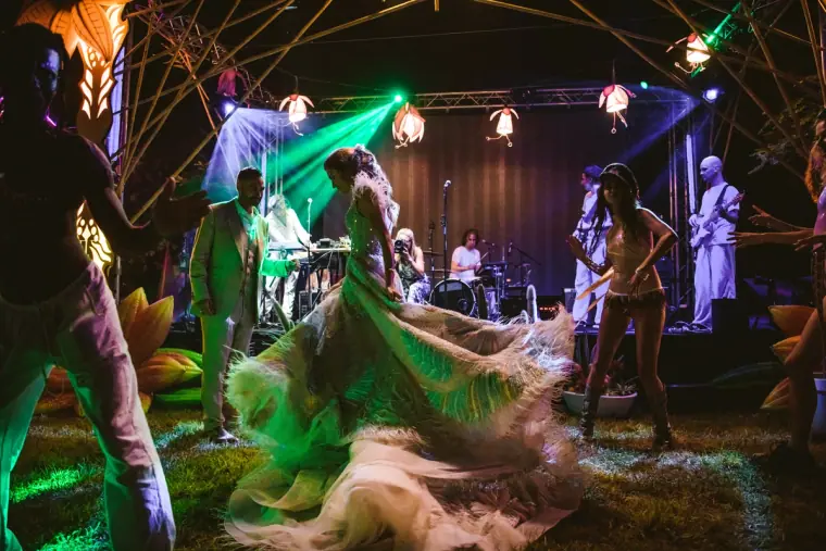 Bride twirling on a green-lit dance floor in front of a live band